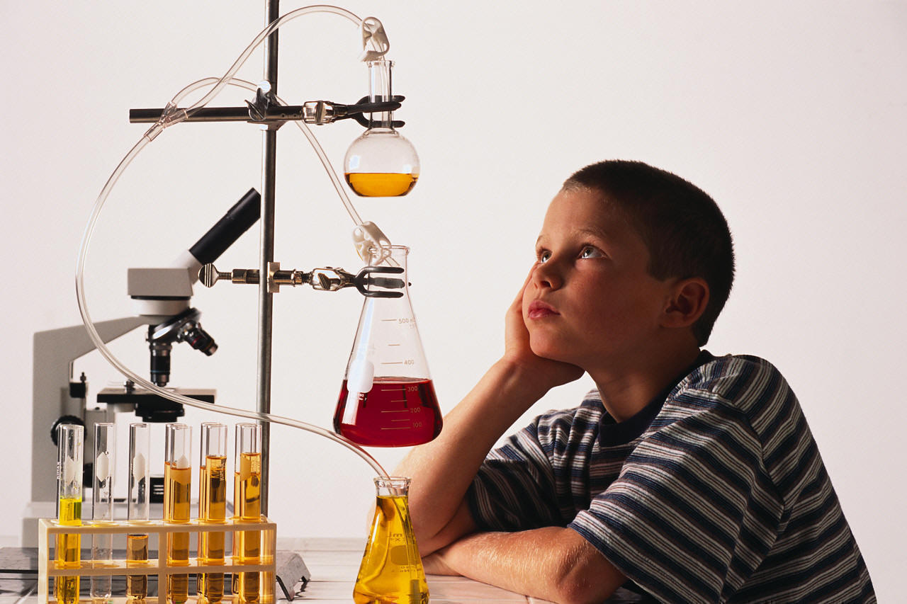 thinking boy sitting at table with science equipment